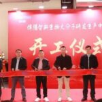 A group of people standing in front of a red ribbon.