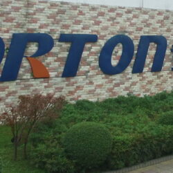 A sign for porton technology in front of a brick building.