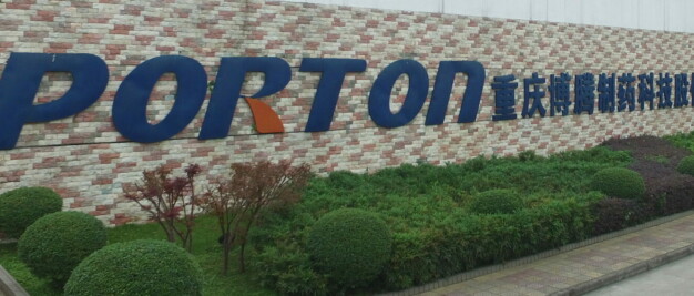 A sign for porton technology in front of a brick building.