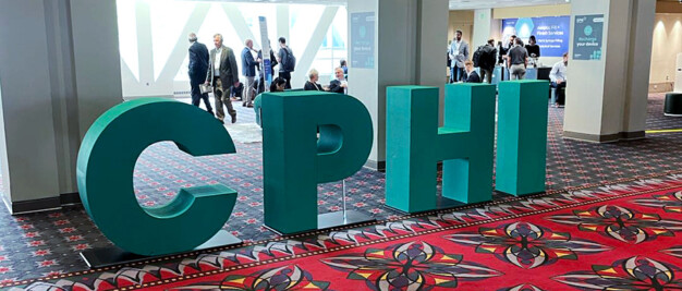 Large green letters spelling "CPHI" are displayed in a carpeted lobby area with people walking and sitting in the background.