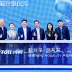 A group of six people in suits stands behind a display table with "PORTON" and Chinese text, giving thumbs up at a company event celebrating the modality capacity upgrade.