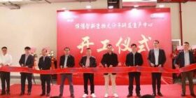 A group of people standing in front of a red ribbon.