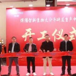 A group of people standing in front of a red ribbon.