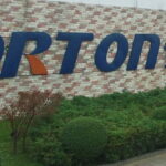 A sign for porton technology in front of a brick building.