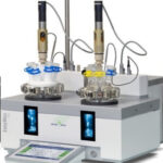 Laboratory equipment with two glass reaction vessels connected to sensors on a digital control unit.