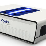 A white Crystal Line electronic device with a blue LED display on top and multiple ports on the sides.